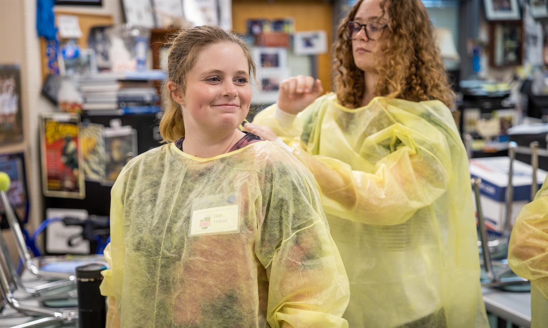 Two girls tie robes for each other